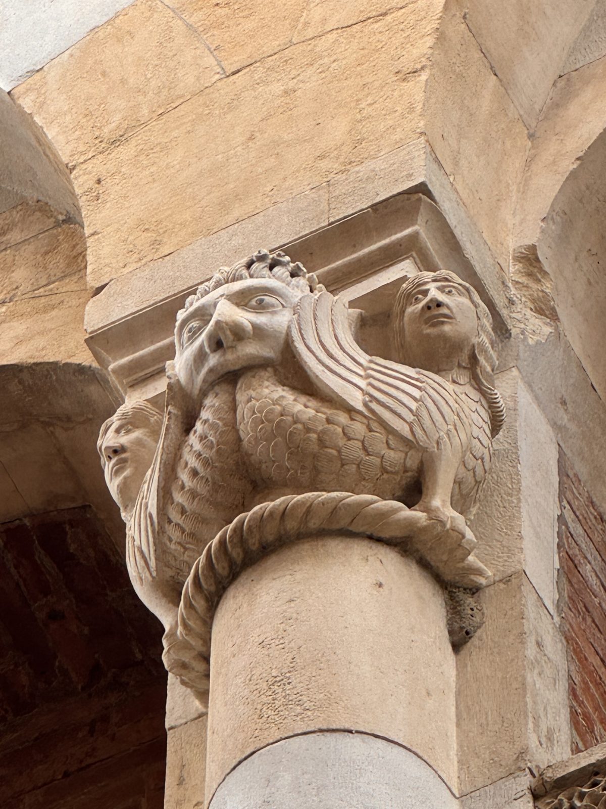 A monstrous head with a scaly, feathered body, flanked by a human face: the coexistence of human and bestial nature in a single being