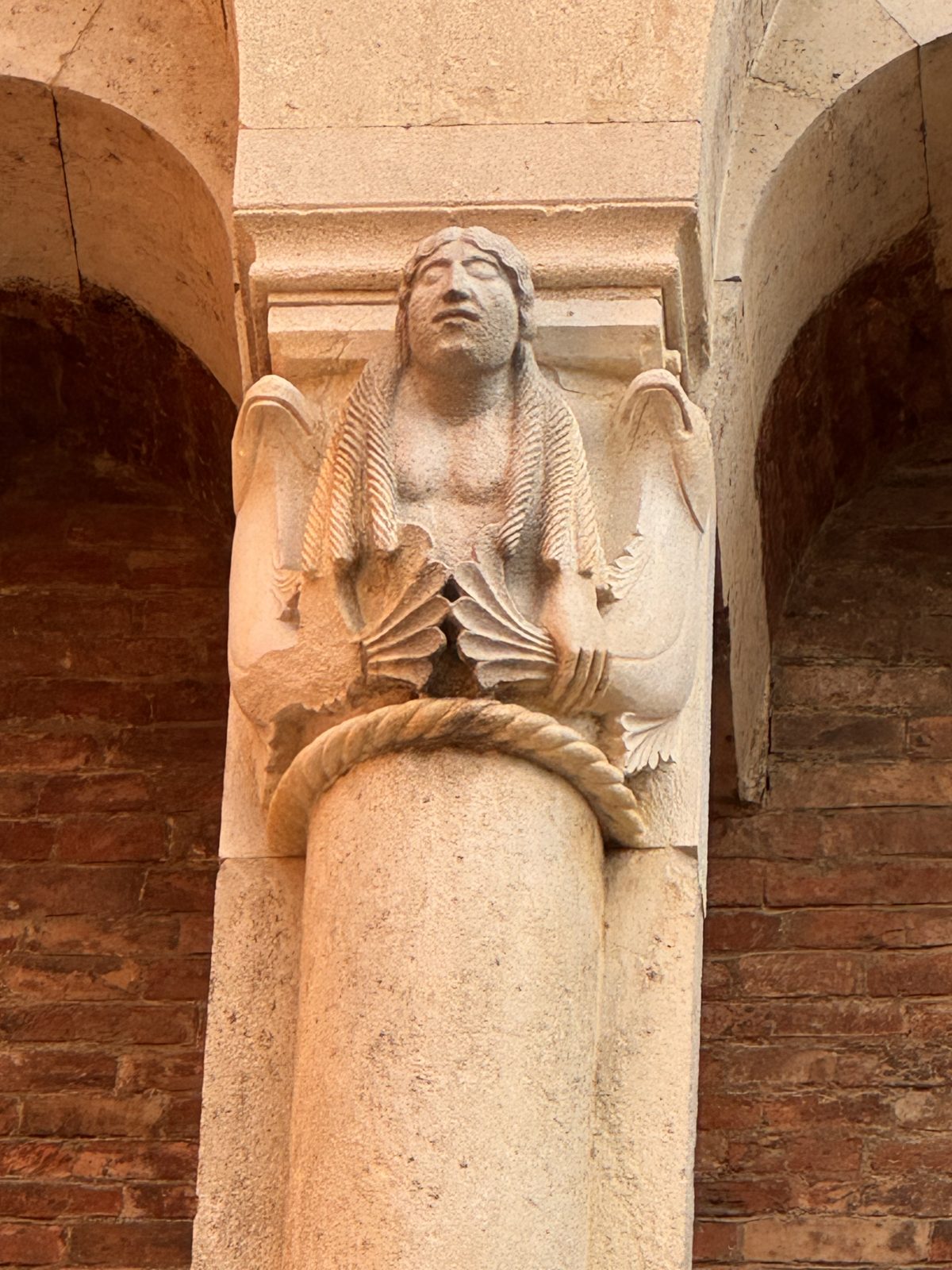 A two-tailed siren holding her tails