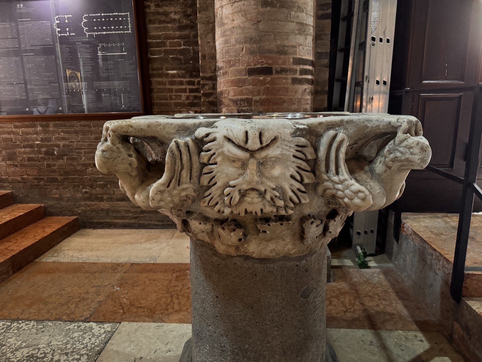 A stone basin carved with a bearded mask and foliage