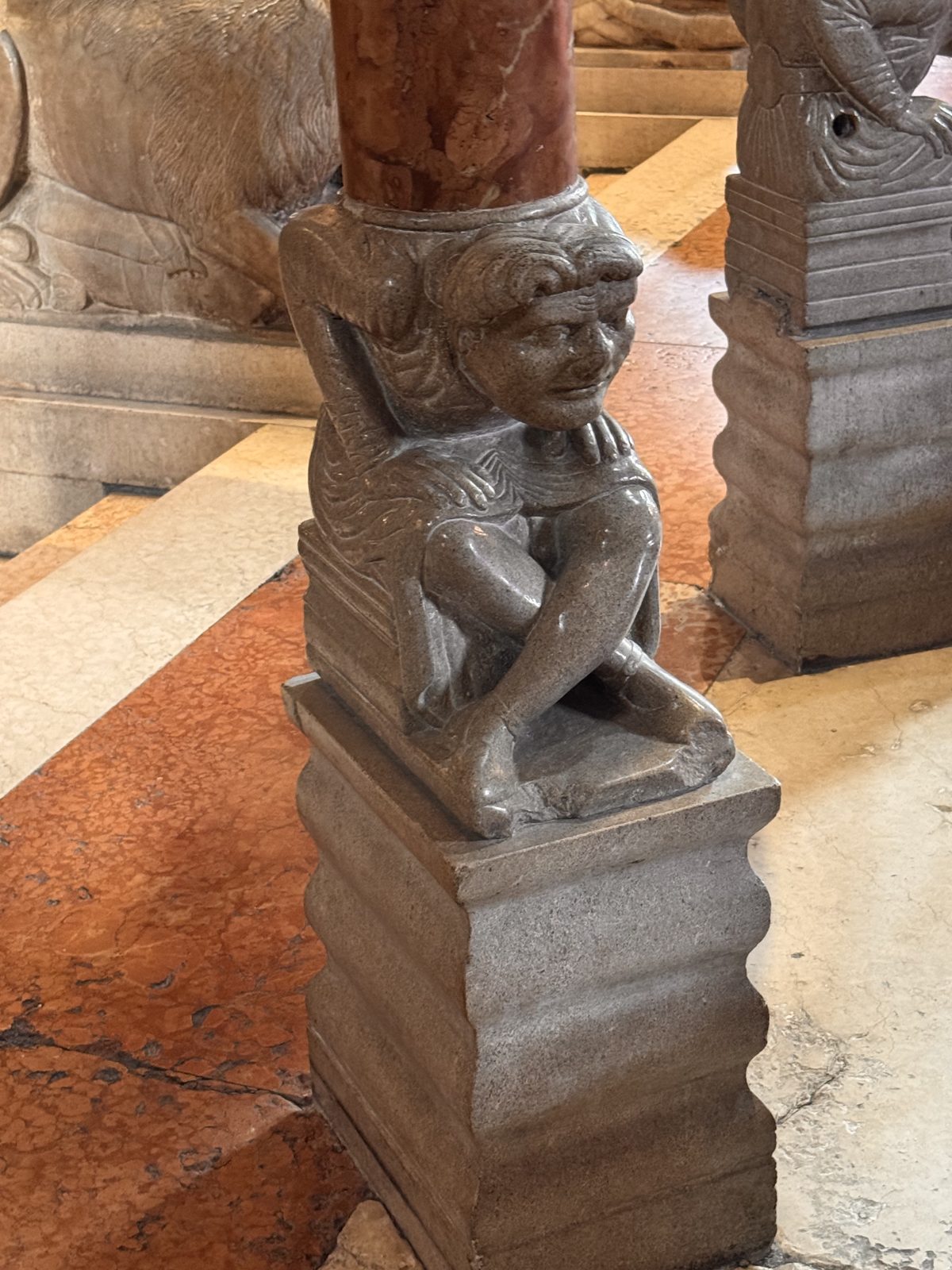 A crouching telamon supporting a column: the human figure bent under the load, a recurring Romanesque image of humanity burdened by sin